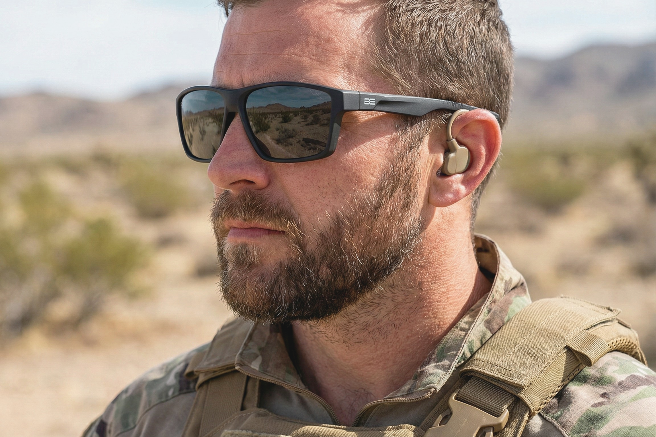 Man wearing sunglasses and a military uniform in a desert setting