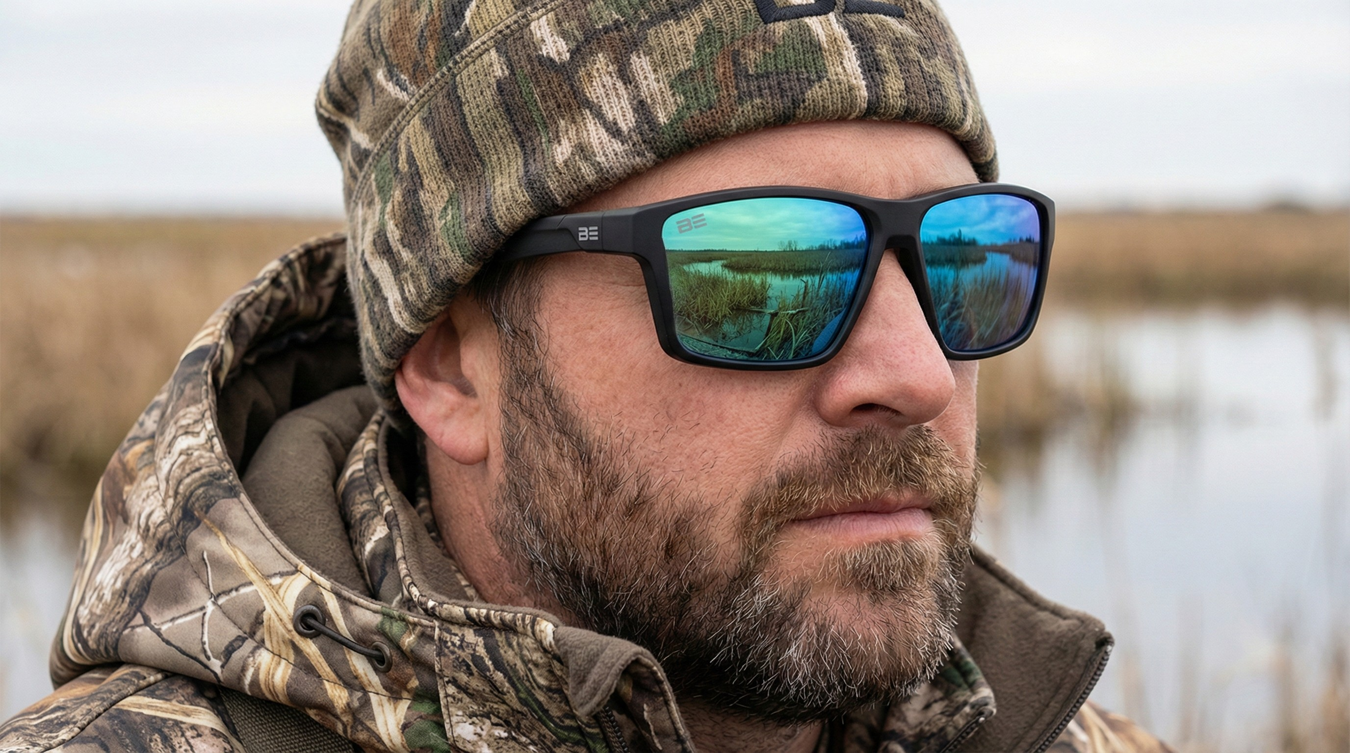 Man wearing camouflage hat and sunglasses with reflective water in background